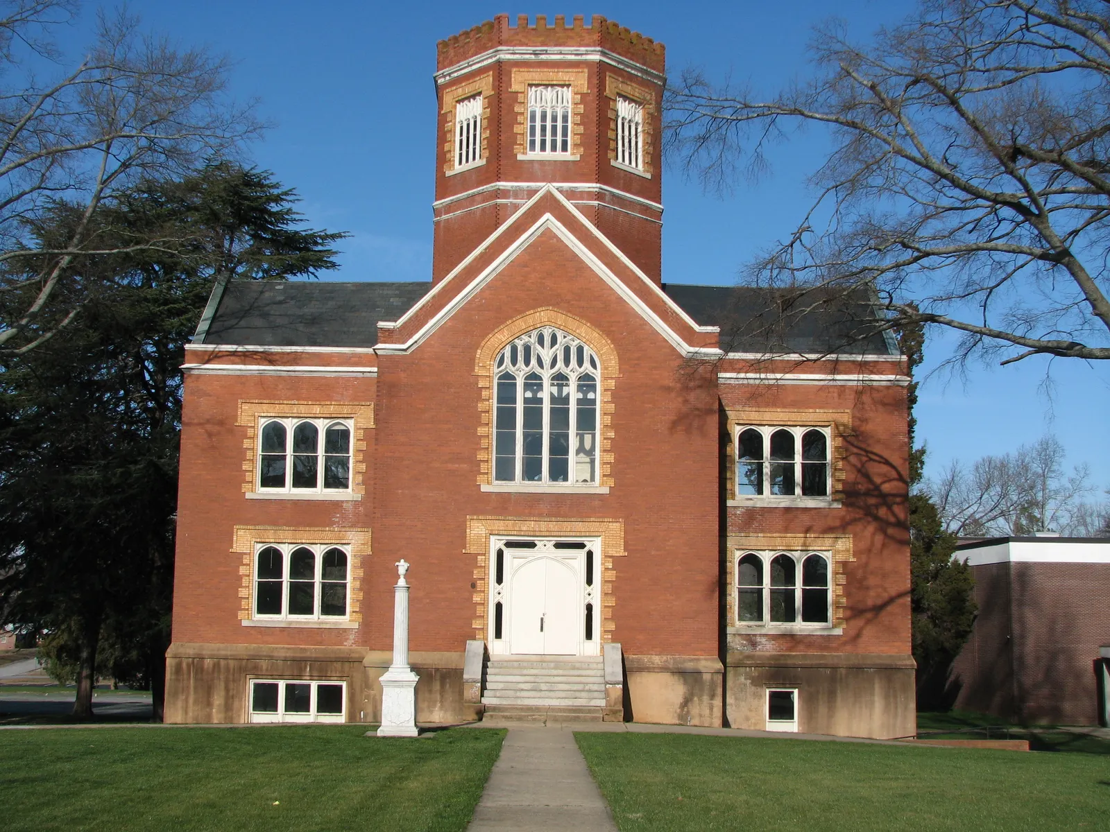 Frontal view of brick building with castle style turret in center.