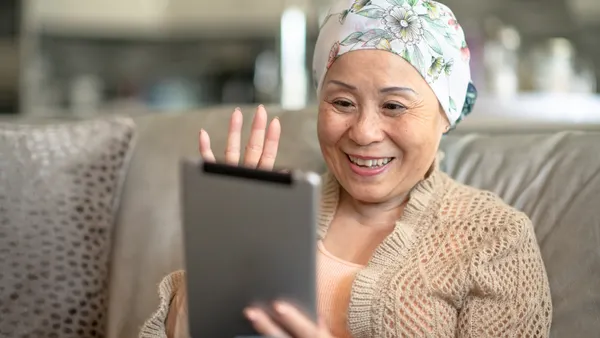 A woman smiles while interacting with someone on her digital tablet