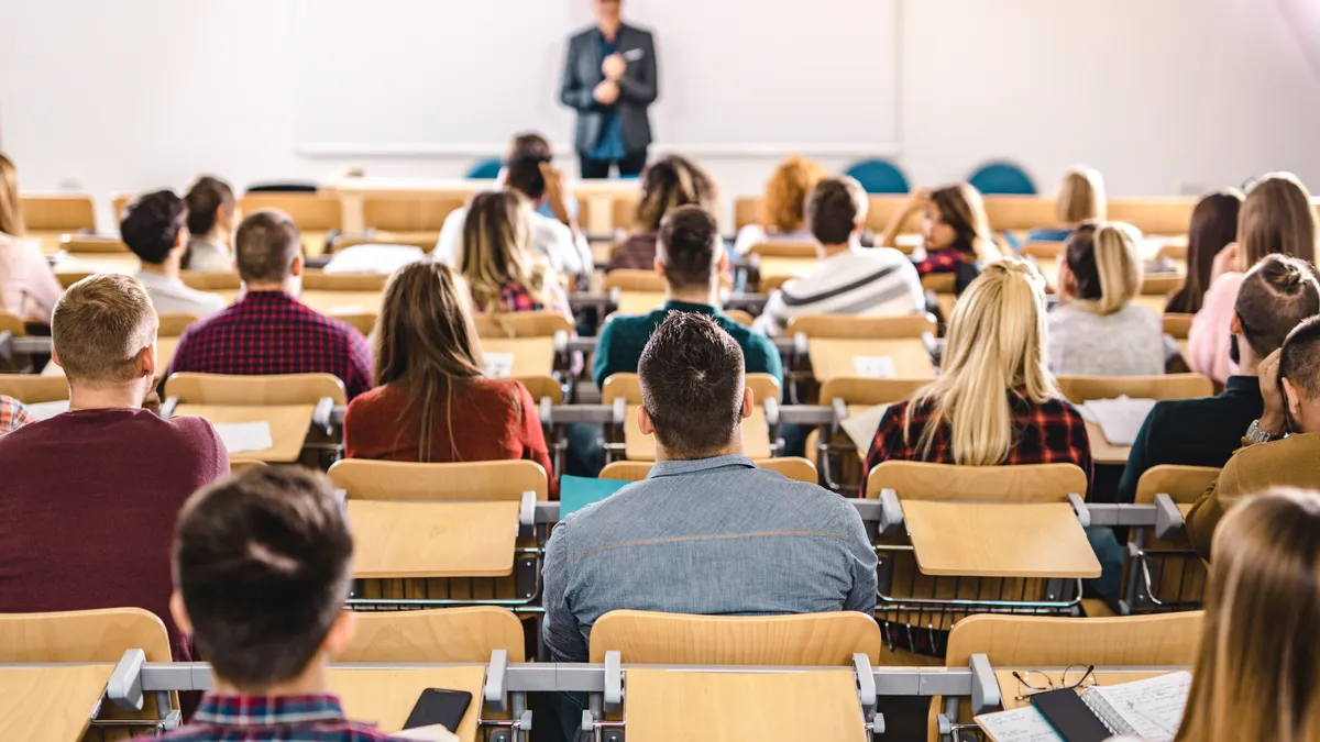 A professor speaks to a crowded room full of students.