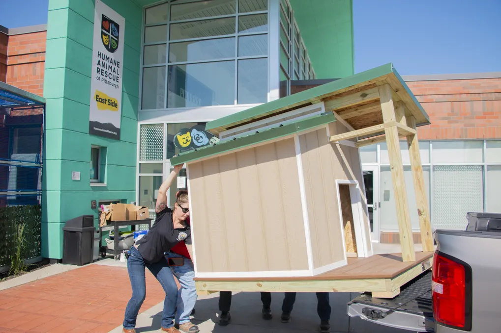 Employees at a animal rescue in Pittsburgh remove a large doghouse from the bed of a pickup truck.