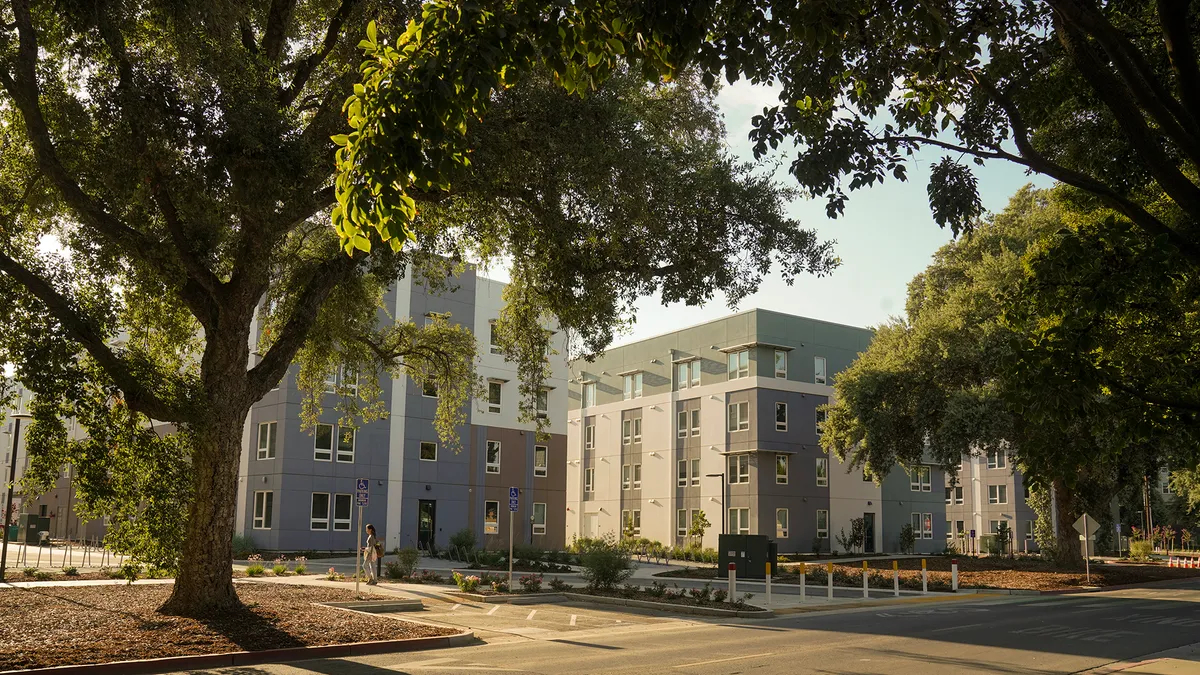 A large, modern-style building surrounded by trees.