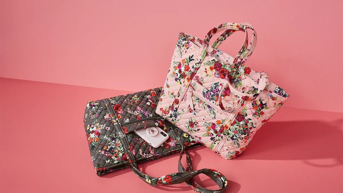 Two black and pink fabric bags with floral patterns against a pink backdrop