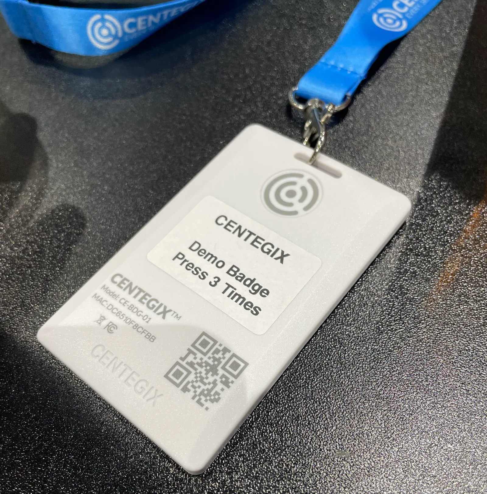 A white panic alarm badge attached to a lanyard lays on a tabletop.