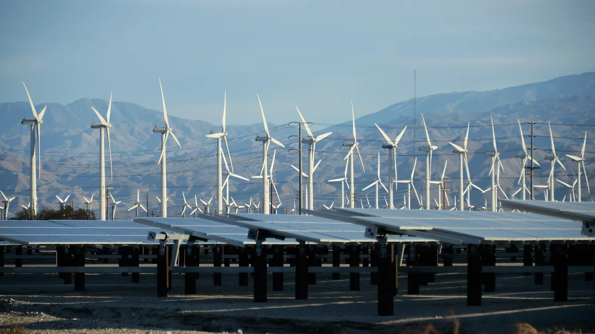 Windmills behind a field of solar panels.