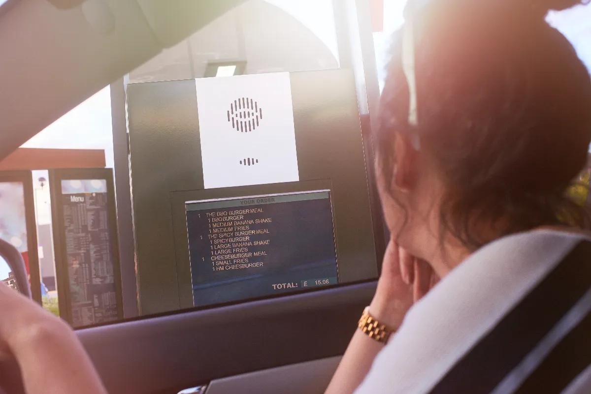 An image of a woman ordering at a drive-thru speaker box.