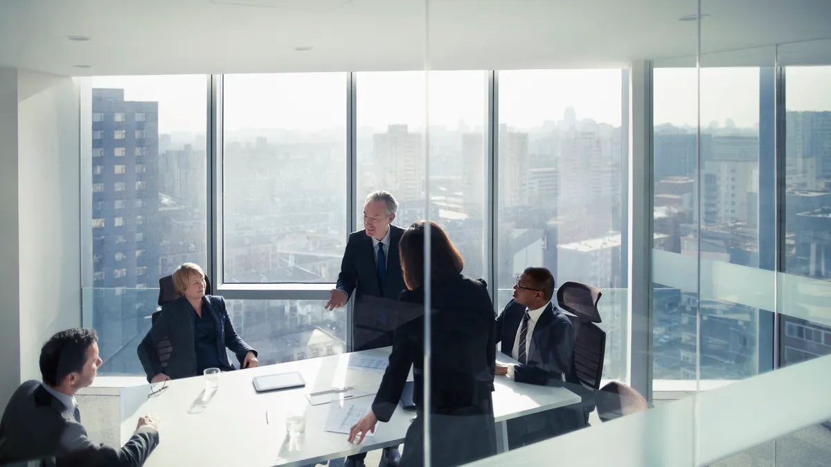 A diverse group of executives talking in meeting room.