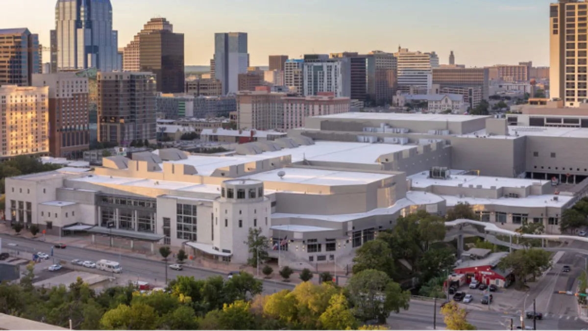 An aerial photograph shows the sprawling convention center building in downtown Austin, Texas.