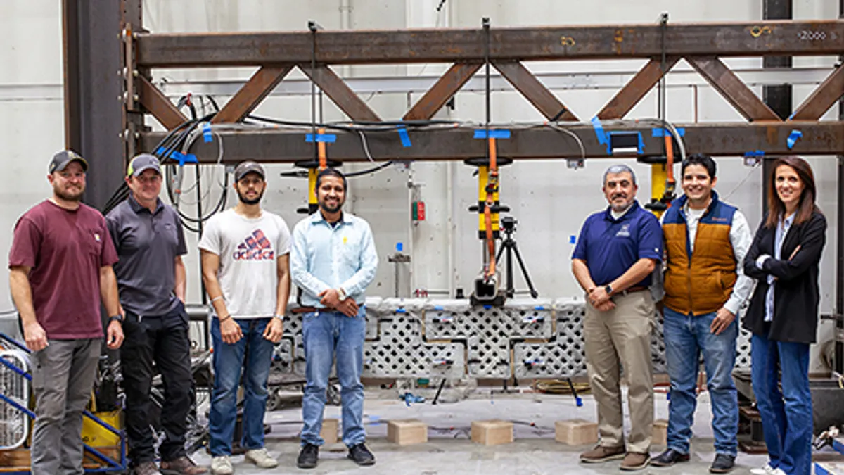 A group of people stand in front of a machine in an indoor industrial setting.