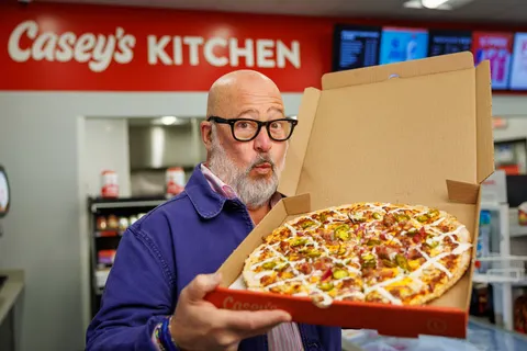 A photo of a person holding an open pizza box with a BBQ brisket pizza inside.