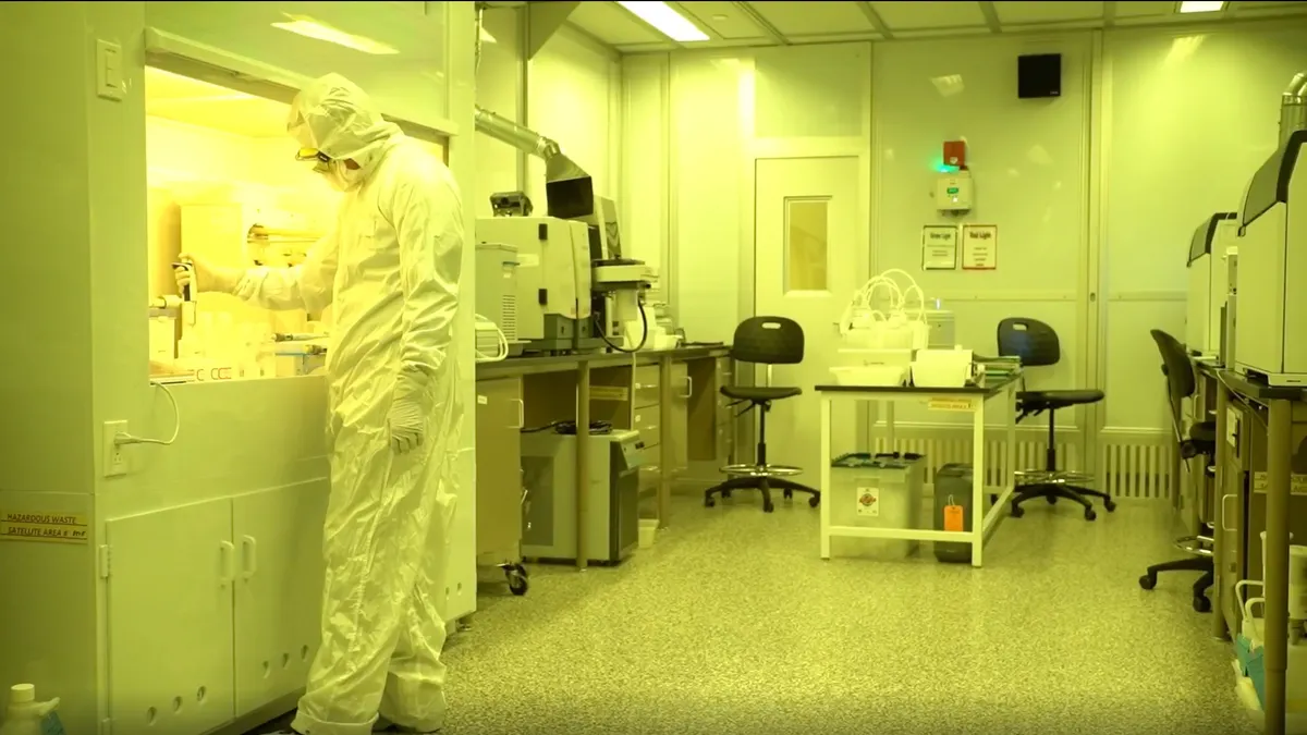A person in a white protective suit works in a lab