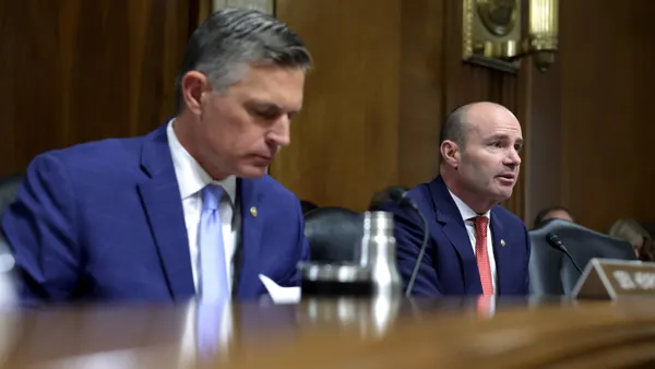 Two men sit at a dais.