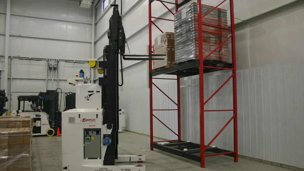 An automated forklift picks up a load from a warehouse rack.