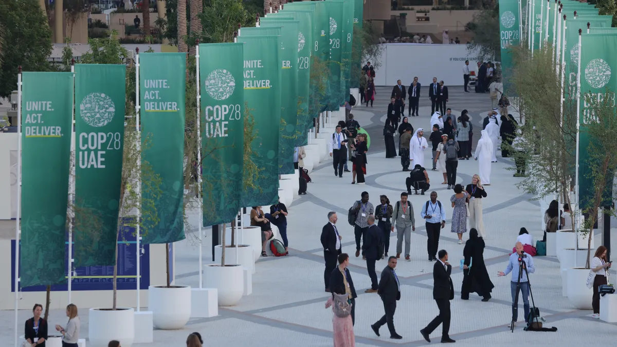 Participants walk around the conference with COP28 UAE flags lining the walkway.