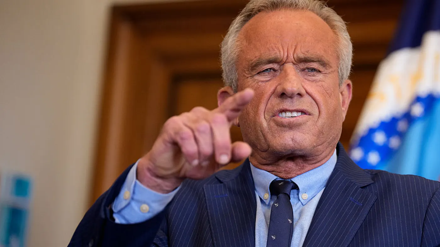Robert F. Kennedy Jr. in a blue stripe suit points while speaking
