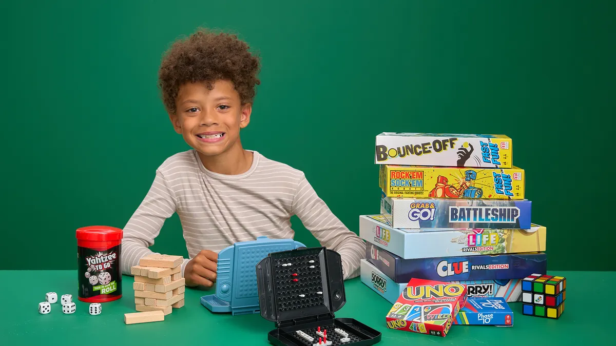 A child sitting next to a stack of board games