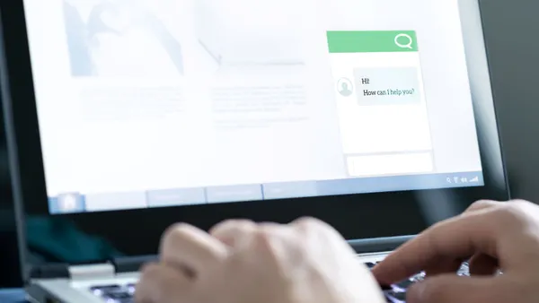 A person types on a laptop screen featuring a chatbot pop-up.