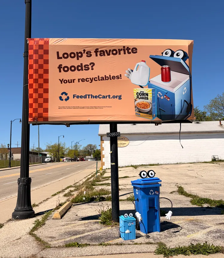 A billboard that reads "Loop's favorite foods? Your recyclables!" with a recycling cart in front