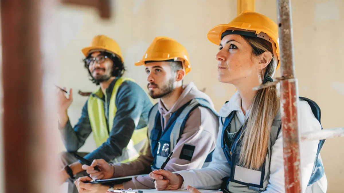 Three construction workers listen intently at a briefing.