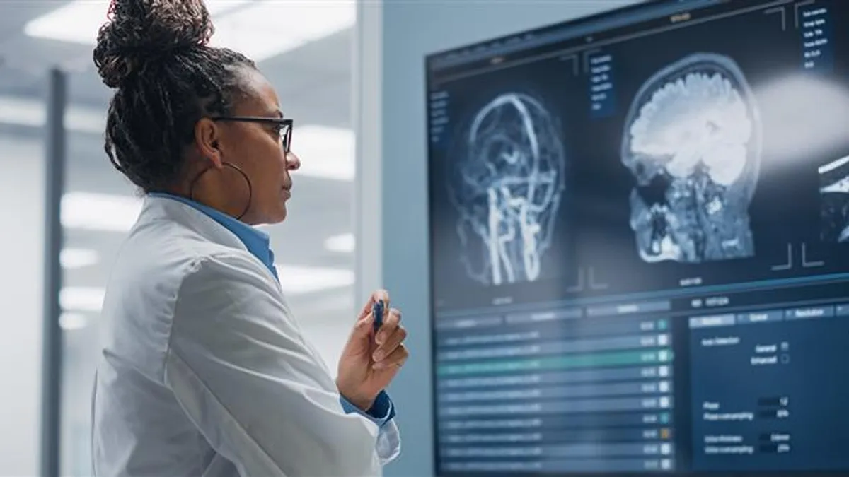 Doctor looks at TV screen with MRI scanned images of a brain