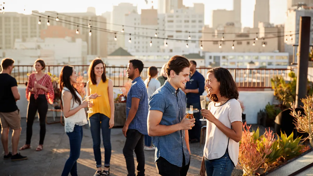 a group of friends on top of a rooftop having a part with a city skyline in the background