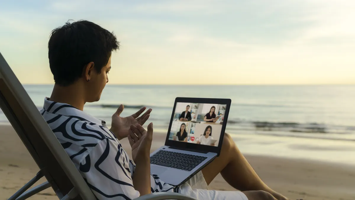 Asian business man having remote video conference call with his business team at the beach during vacation in holiday.