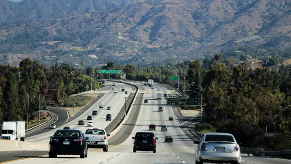 Highway traffic along Interstate 215 with Southern California mountains in the background.