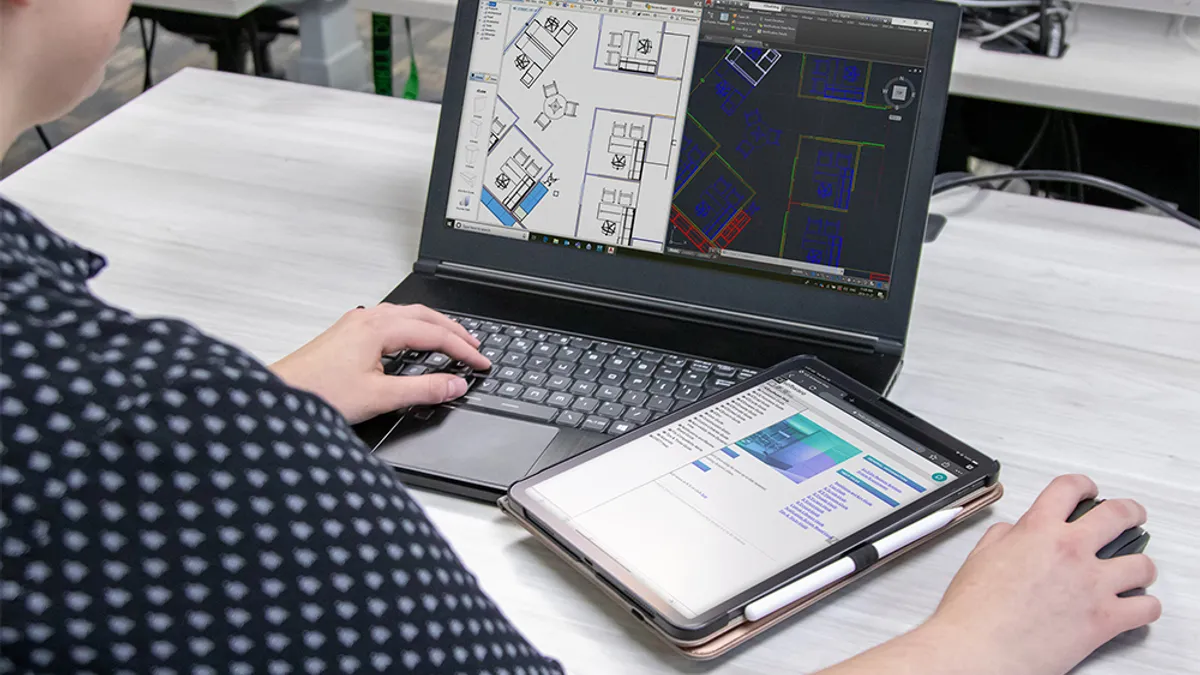 Young professional working on construction project at desk on laptop and tablet