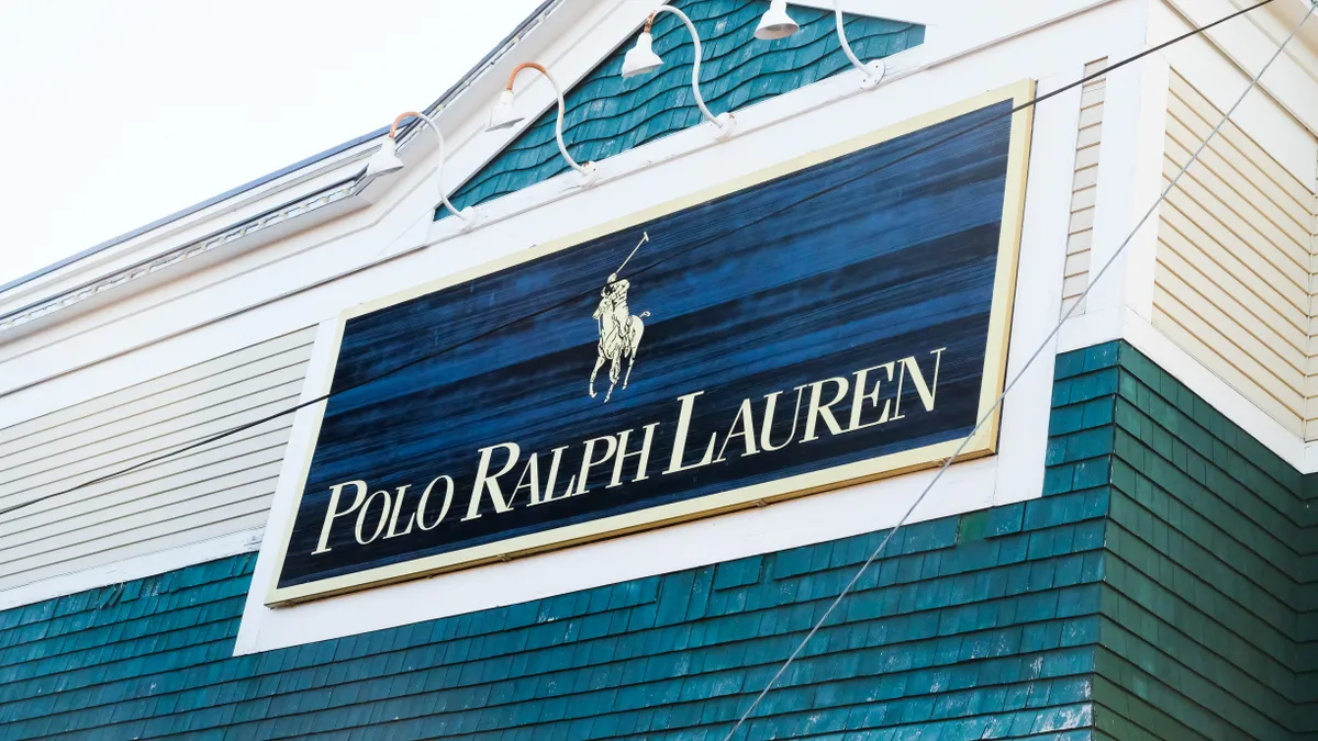 A blue sign with the Polo horse-and-rider logo and the words "Polo Ralph Lauren" hangs from a clapboard building.