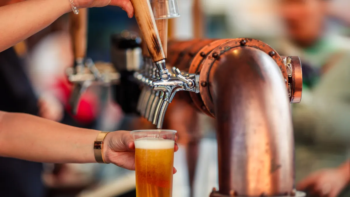 A bartender pours a draft beer.