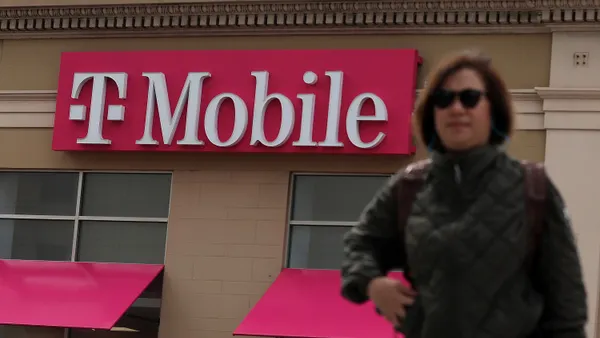 A person walks in front of a T-Mobile storefront.