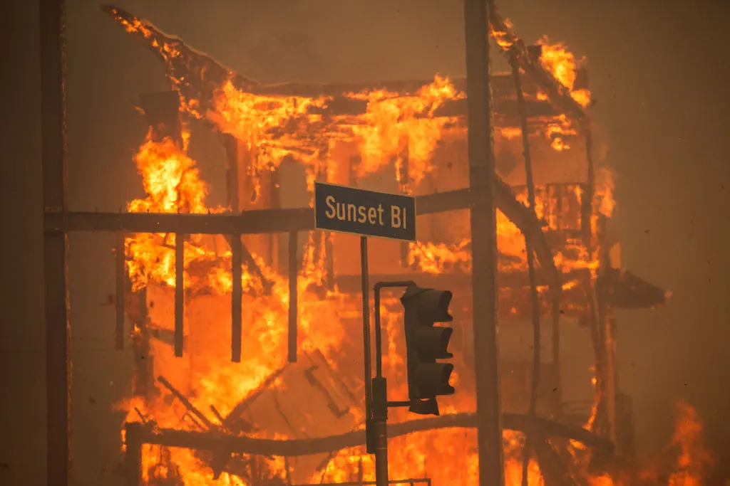 A street sign in front of a massive fire.