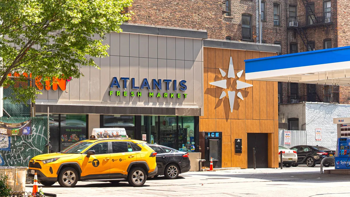 A photo of a convenience store. A sign over the door reads "Atlantis Fresh Market."