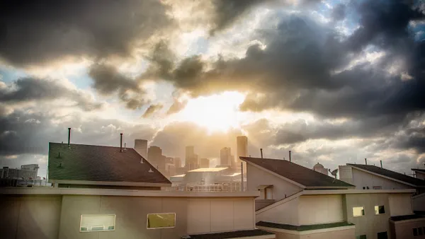 Homes in foreground, clouds clearing over skyline in the background.