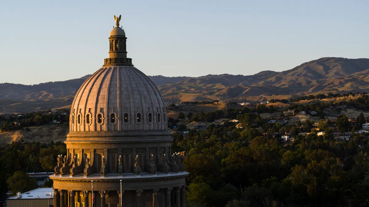 Sandstone neoclassical Idaho State Capitol building against mountain backdrop. Afternoon light illuminates the dome.