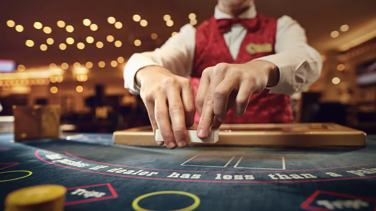 A croupier holds poker cards in his hands at a table in a casino.