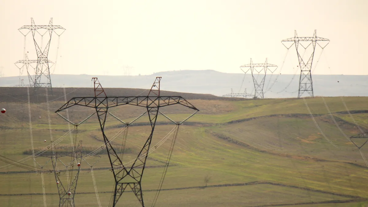 Transmission lines stretch across rolling green fields