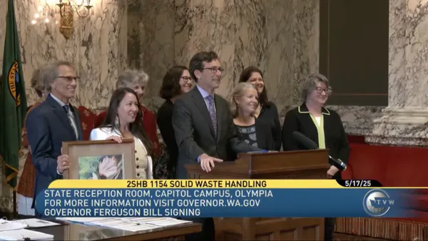 Washington Gov. Bob Ferguson poses with a crowd of people in Olympia after signing a bill