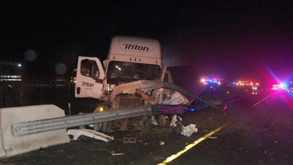 The Triton Logistics tractor involved in the crash, shown in the dark with emergency vehicle lights in the background.