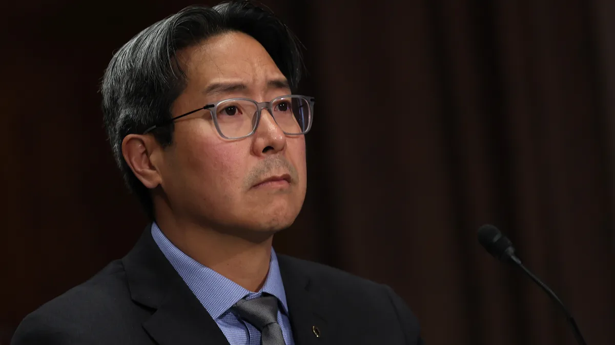 Michael Hsu, acting comptroller of the currency, appears before a Congressional committee wearing a suit.