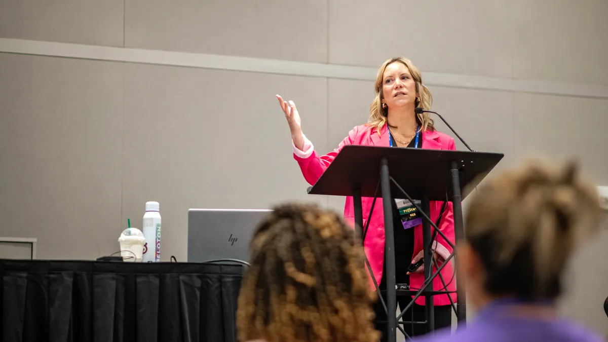 Michelle Clarke stands at the front of a room addressing a crowd of ASCA conference attendees