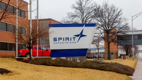 A blue and white Spirit AeroSystems sign in front of a red brick building.