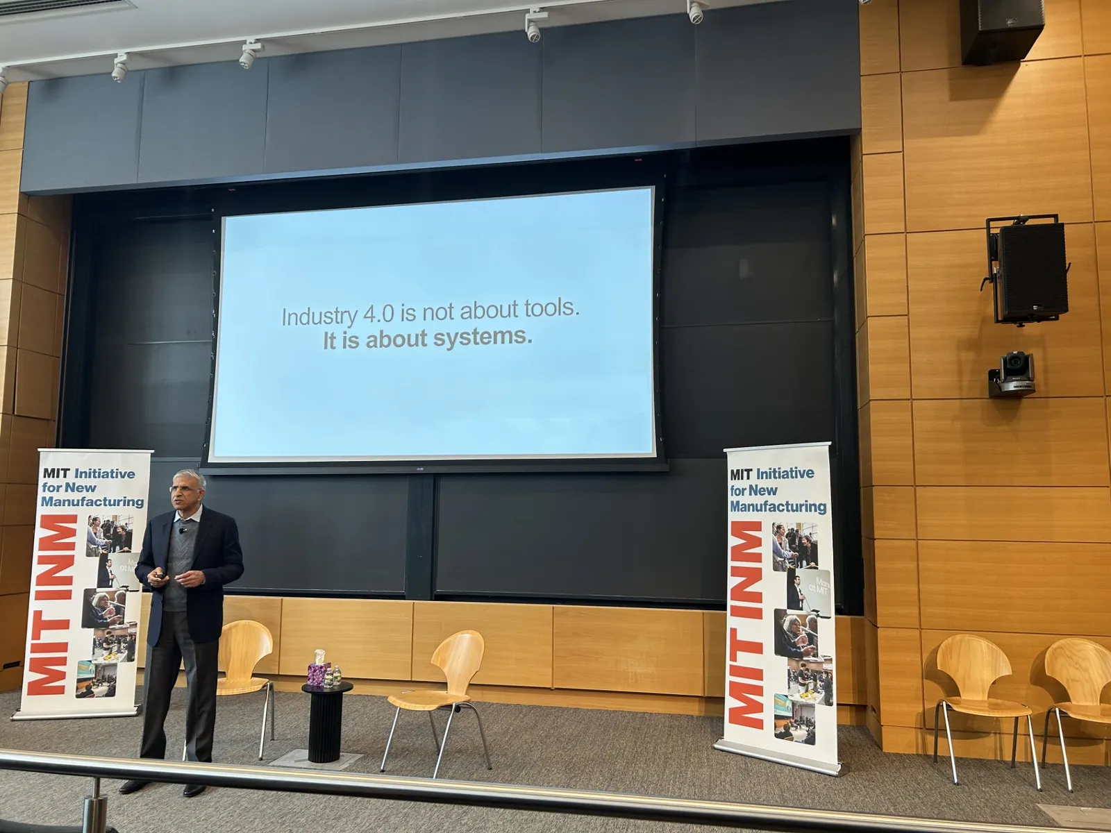 Magna International CEO Swamy Kotagiri stands in front of a screen that says "Industry 4.0 is not about tools. It is about systems."