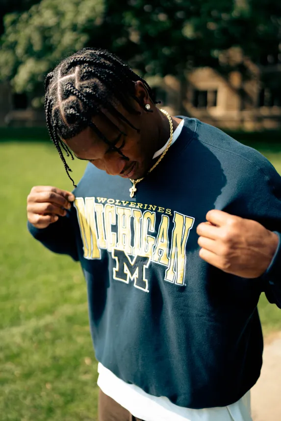 A person wearing a sweatshirt with the University of Michigan&#x27;s logo on it from Hollister&#x27;s Collegiate Graphics Shop