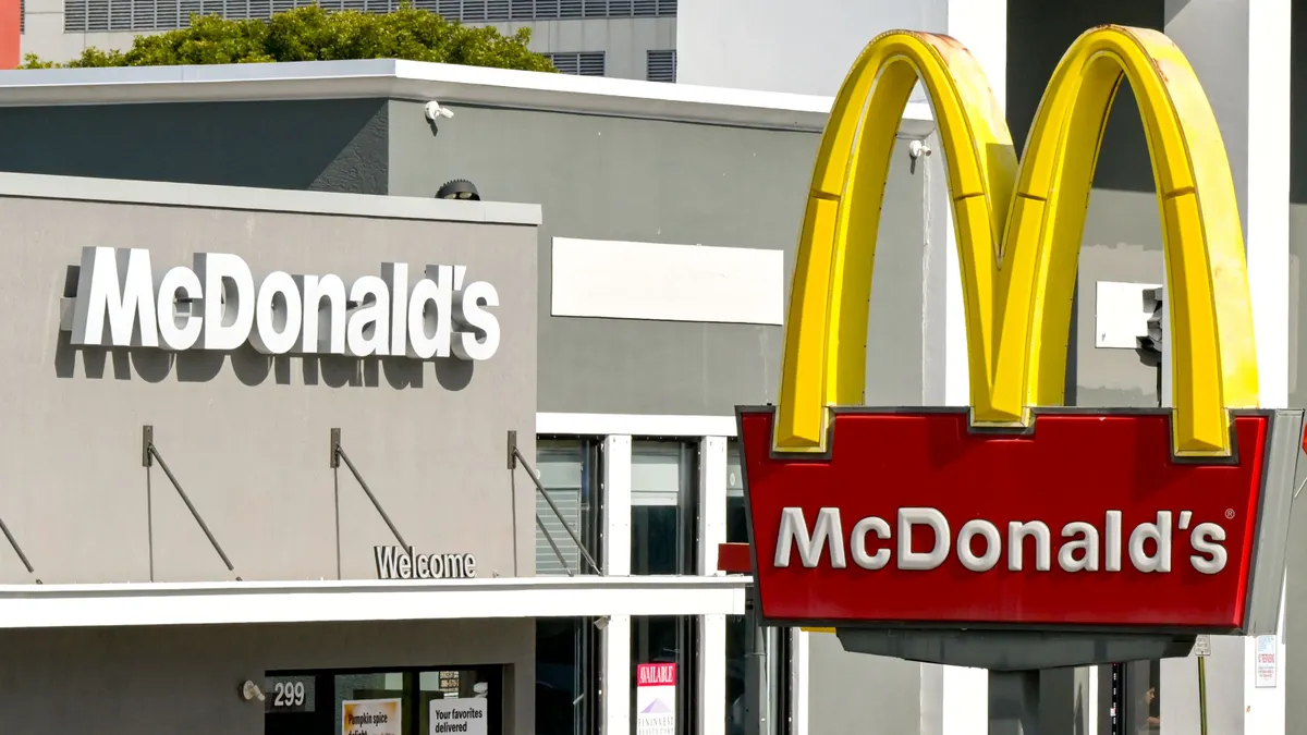An image of a McDonald's with a sign in the forefront and a gray building in the background.