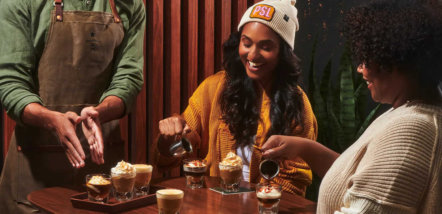 A person in a PSL hat sits at a table pouring something into a glass.