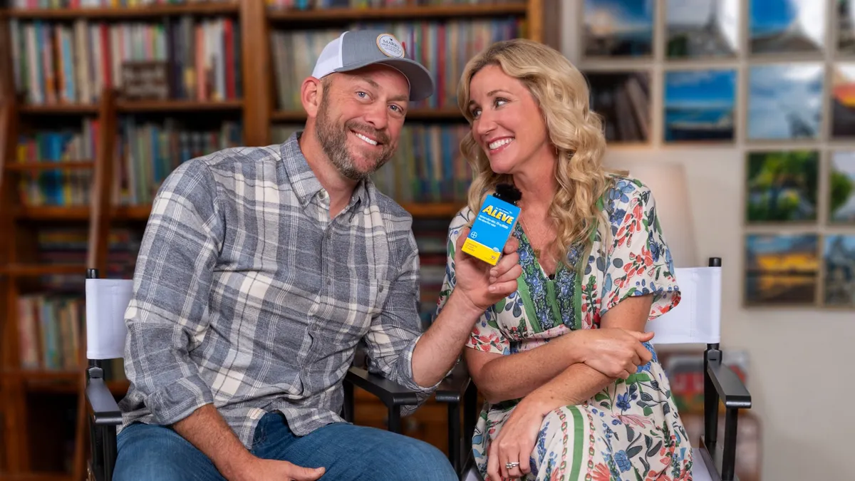 Jenny and Dave Marrs sitting on chairs. Dave is holding a box of Aleve.
