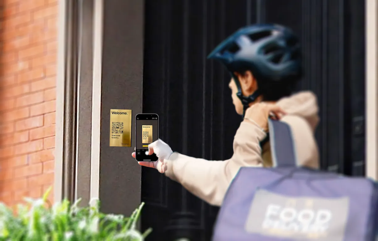 A person holds their phone in front of a metal plaque with a QR code on it.