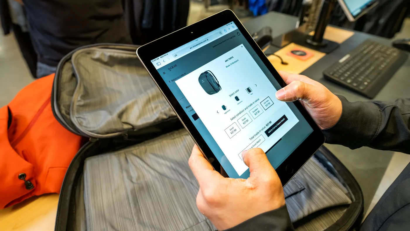 A person holds a tablet and looks at clothing.