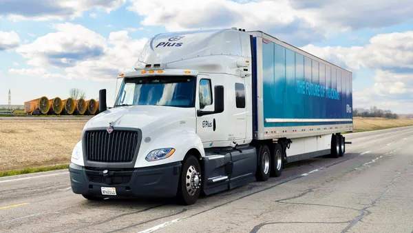 A truck equipped with Plus' autonomous technology on the road with blue skies and white clouds in the background.
