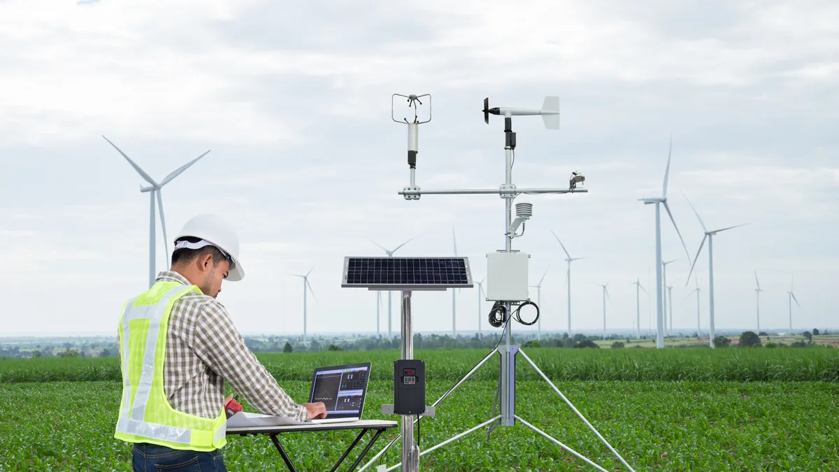 Engineer using computer collect data with meteorological instrument to measure the wind speed, temperature and humidity and solar cell system on corn field background